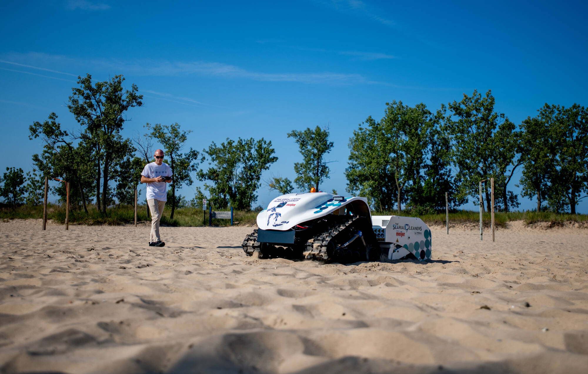 Gautier Peers, with Poralu Marine, left, uses a remote control to demonstrate the BeBot, an eco-friendly beach cleaning robot, on Pere Marquette Beach August 23. The BeBot and Pixie Drone, funded by Meijer, will capture and clean up litter. Grand Valle...